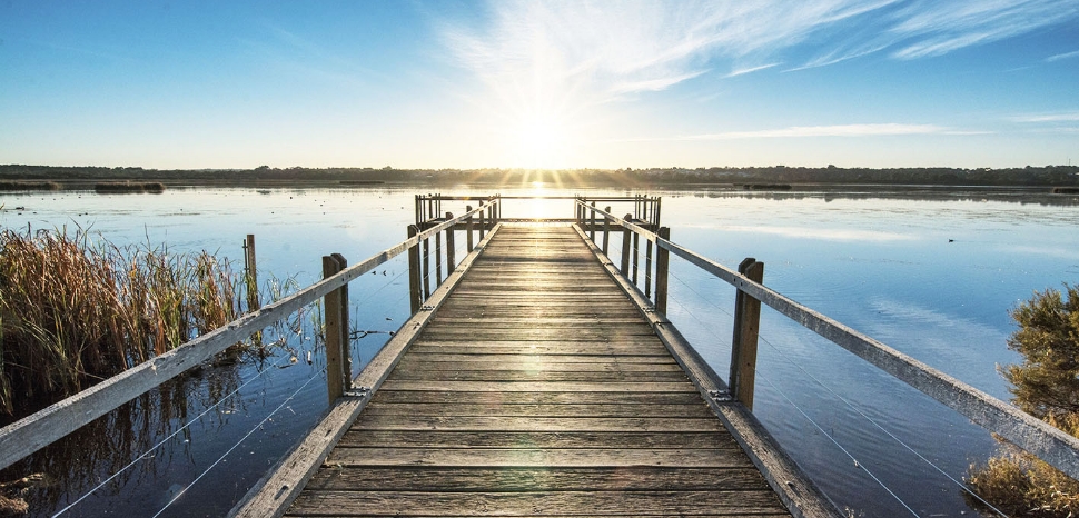 Belle jetee en bois au bord de l ocean calme avec le beau coucher de soleil sur l horizon