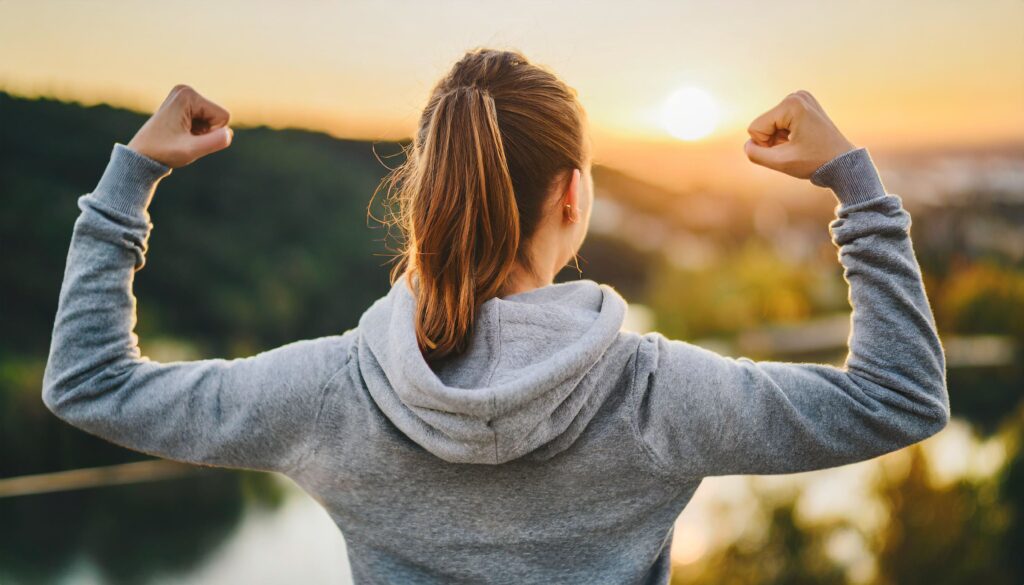 Woman flexing biceps gazing sunrise symbolizing motivation empowerment (1)