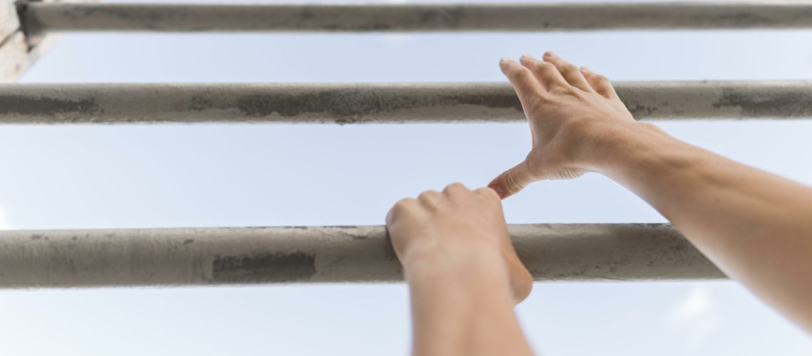 Low angle woman climbing metal bars